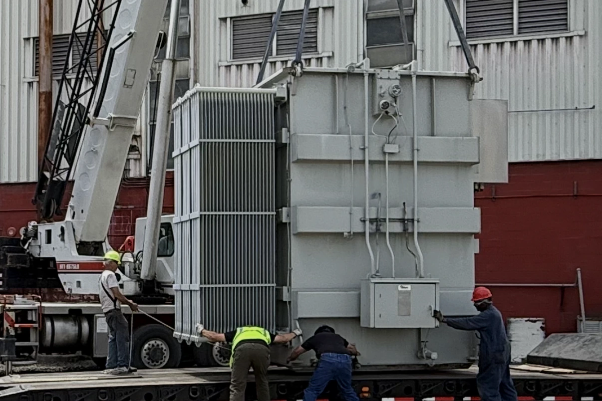 Crane lifting a power transformer onto a lowboy trailer while the removal crew guides the load — Anaheim, CA